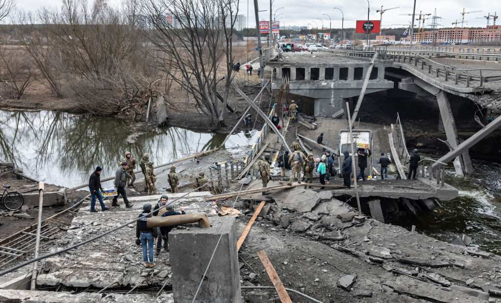 People cross a destroyed bridge as they evacuate the city of Irpin, northwest of Kyiv, during a heavy shelling and bombing.