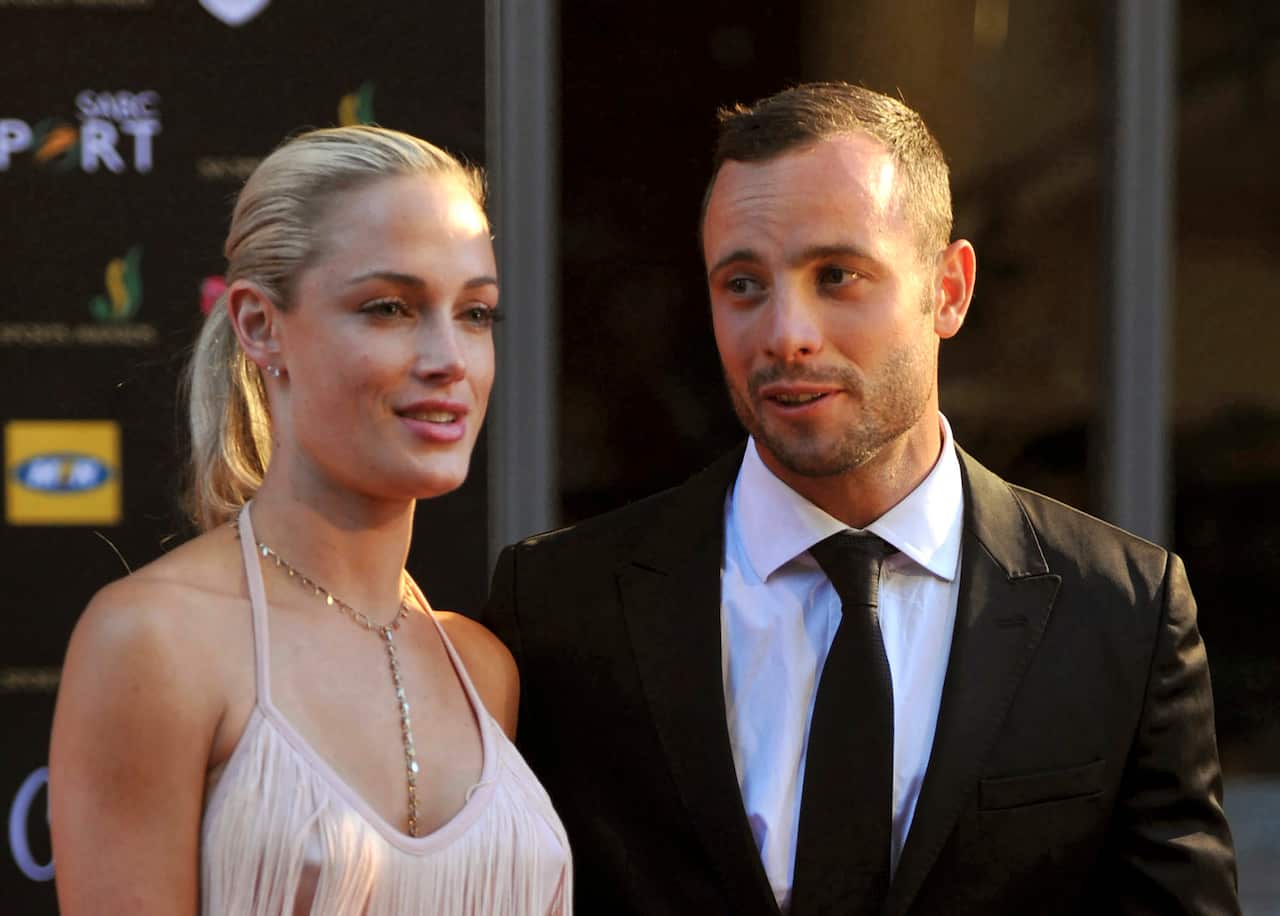 A woman in a high ponytail stands alongside a man in a suit.