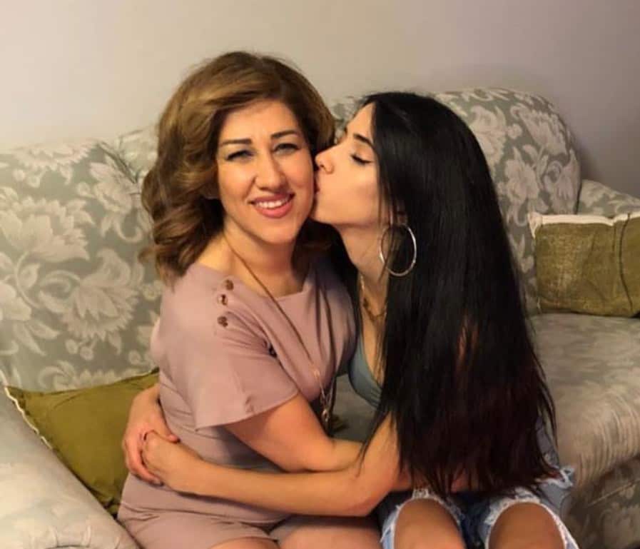 A mother and daughter sit on a couch together