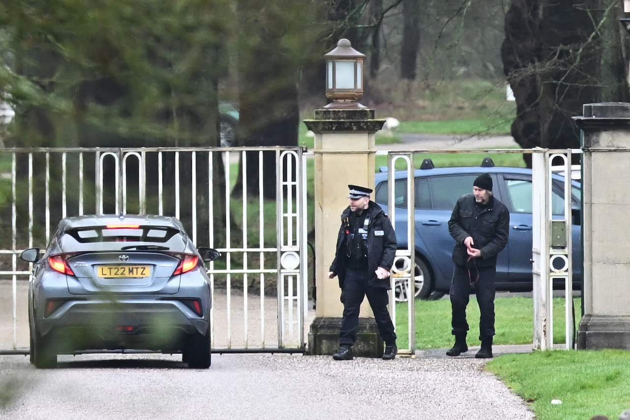 Police officers standing by a gate with a car parked nearby