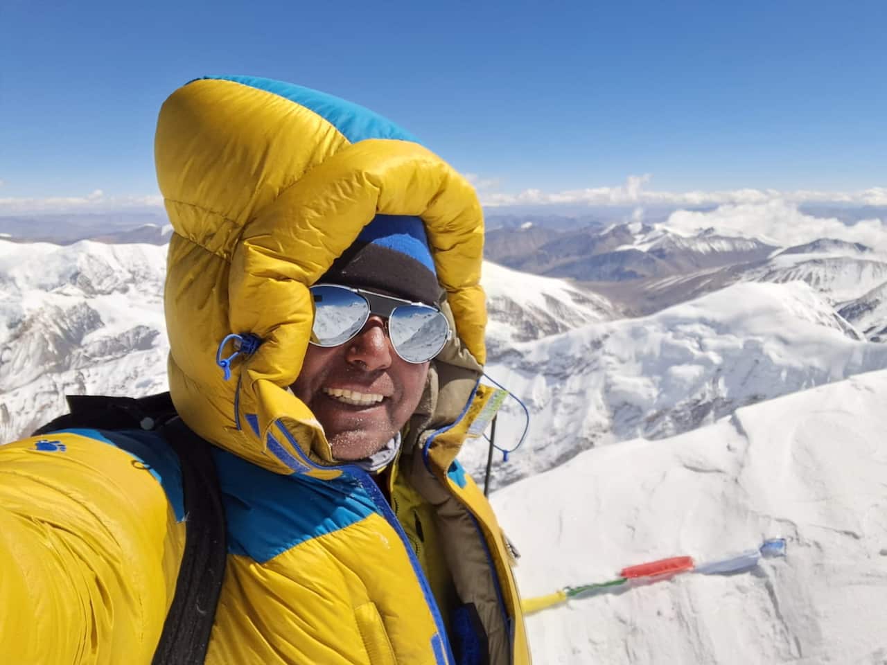 A man wearing a yellow jacket and sunglasses.