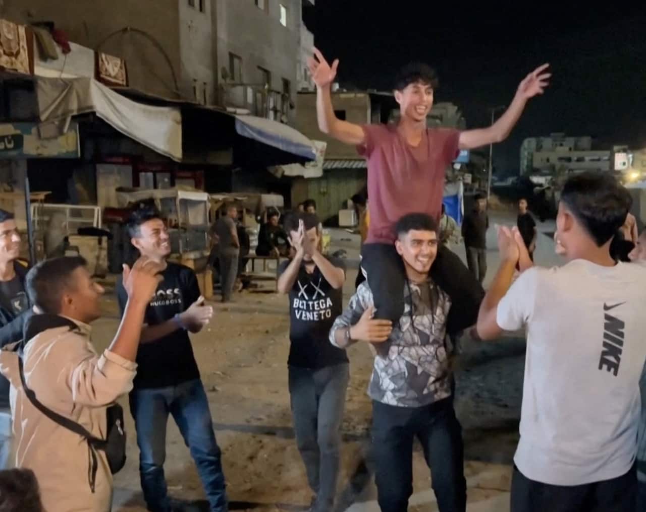 Young Palestinian men celebrate on the street.