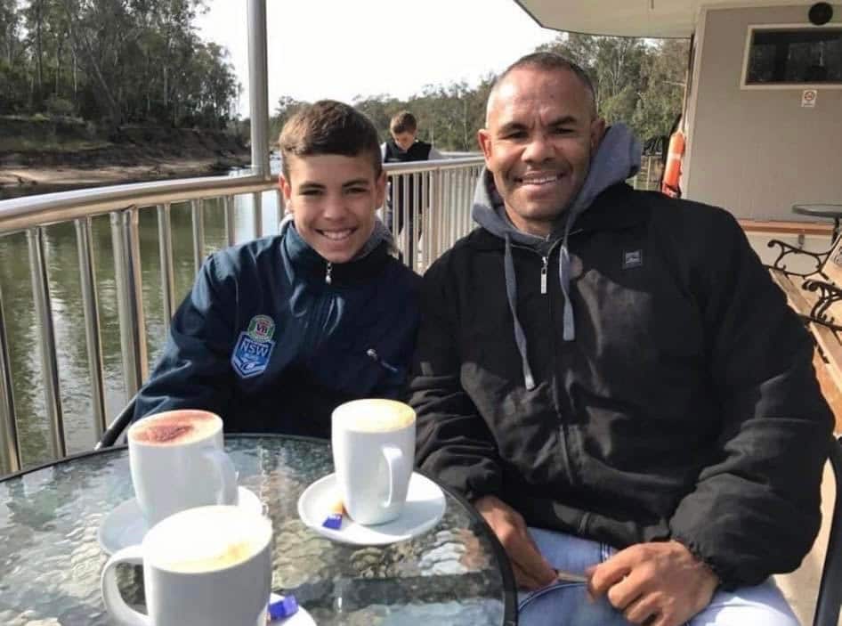 son and father sit together at a cafe smiling