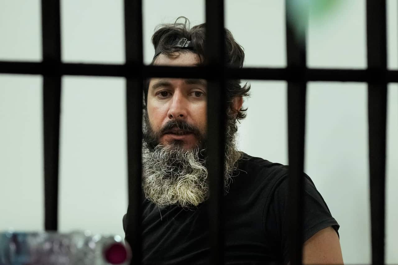 A man with a gray beard behind bars