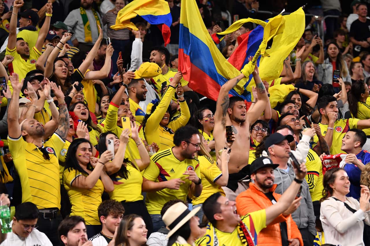 A crowd of people in yellow shirts celebrating and waving yellow flags.