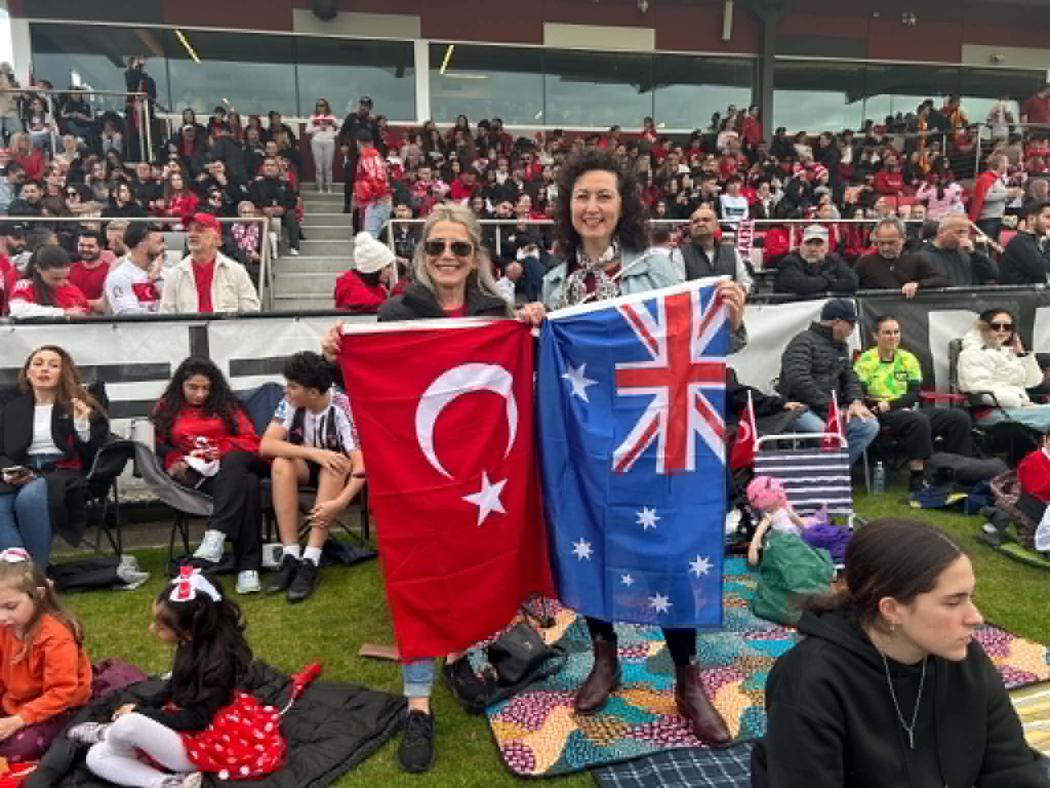 Türk ve Avustralya bayraklarını tutan Melborune Türk toplum bireyleri. SBS Turkish. jfif