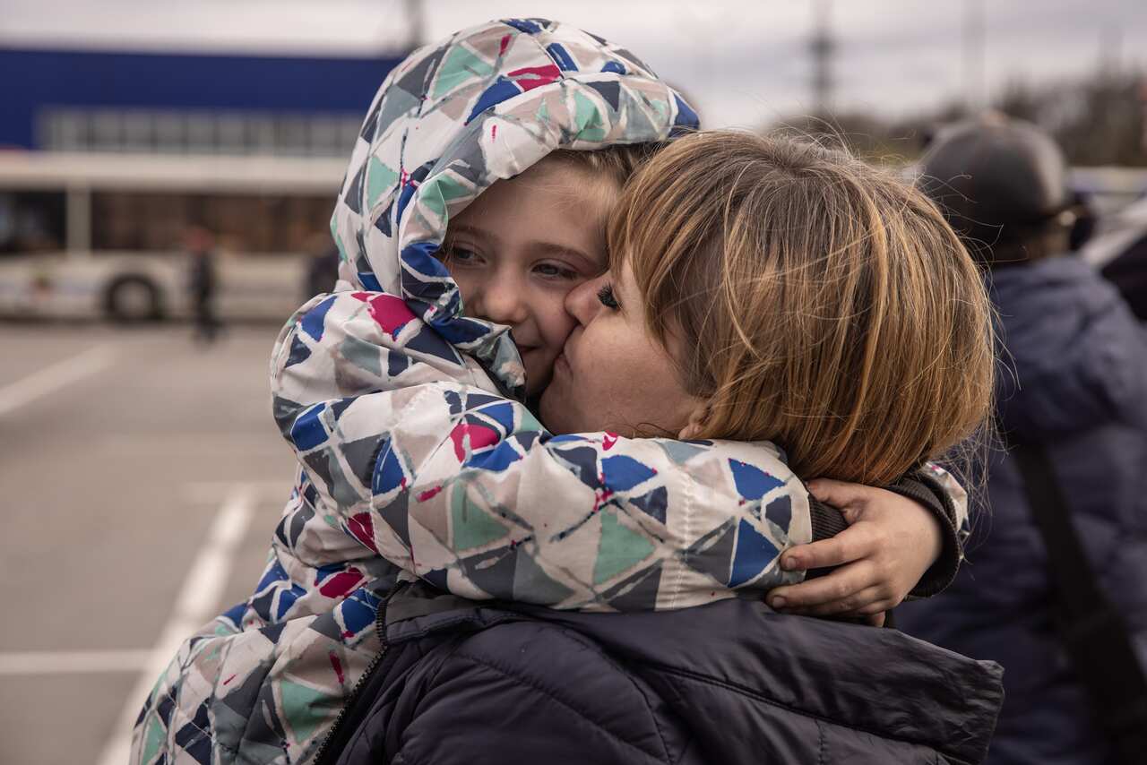 A woman hugs and kisses her granddaughter in a right embrace.