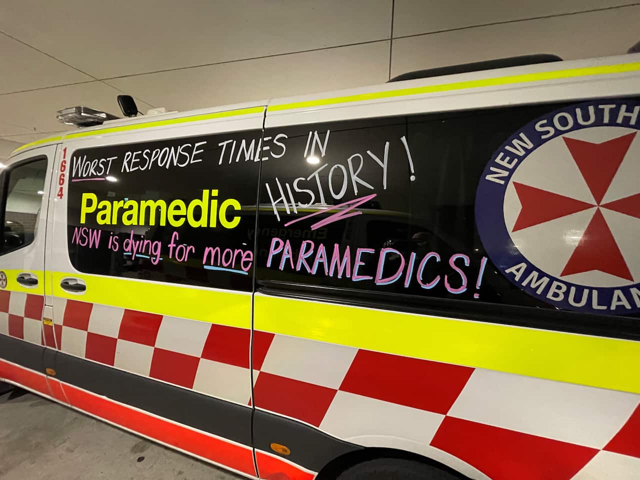 Chalk messages written on an ambulance van that read: "worst response times in history!" and "NSW is dying for more paramedics". 