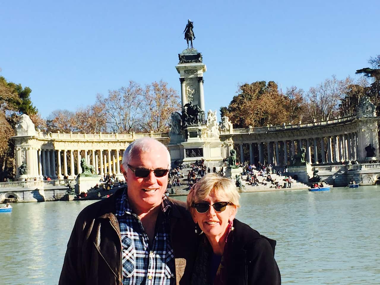 A holiday photo of a smiling couple next to a fountain.