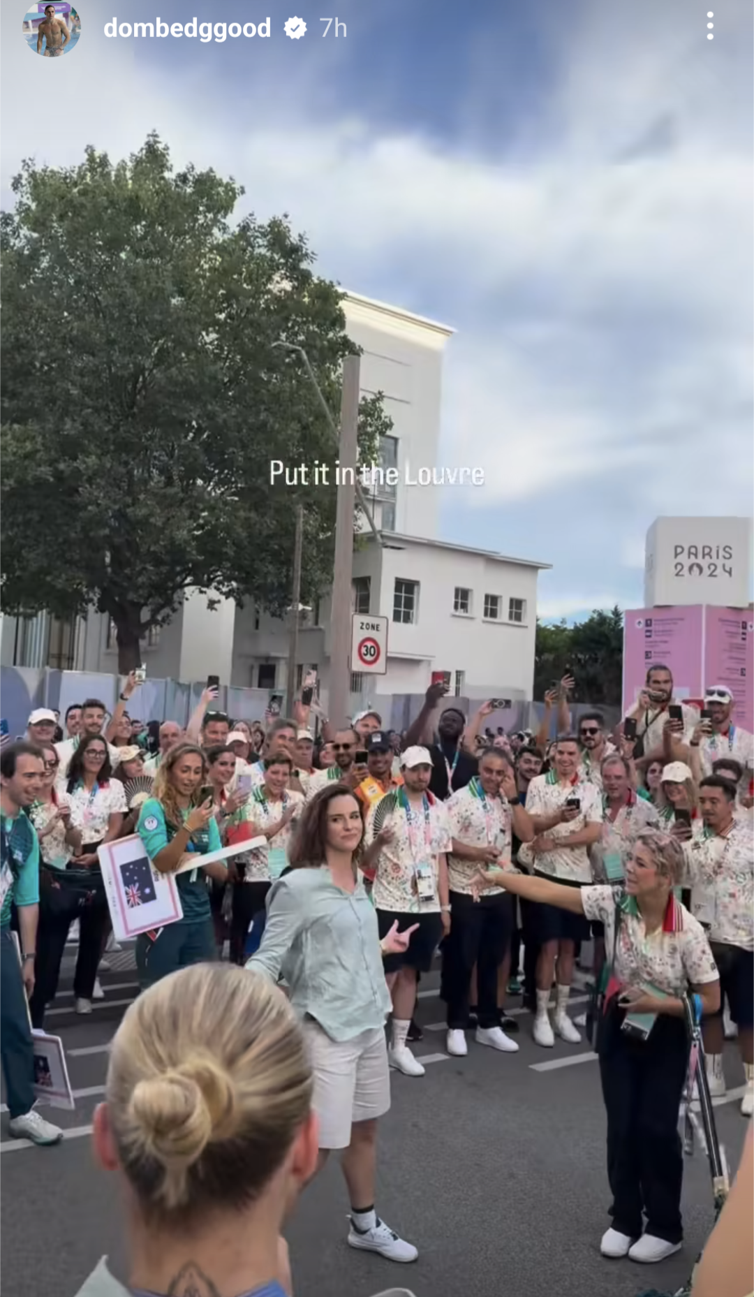A woman dances on the street surrounded by people cheering her on