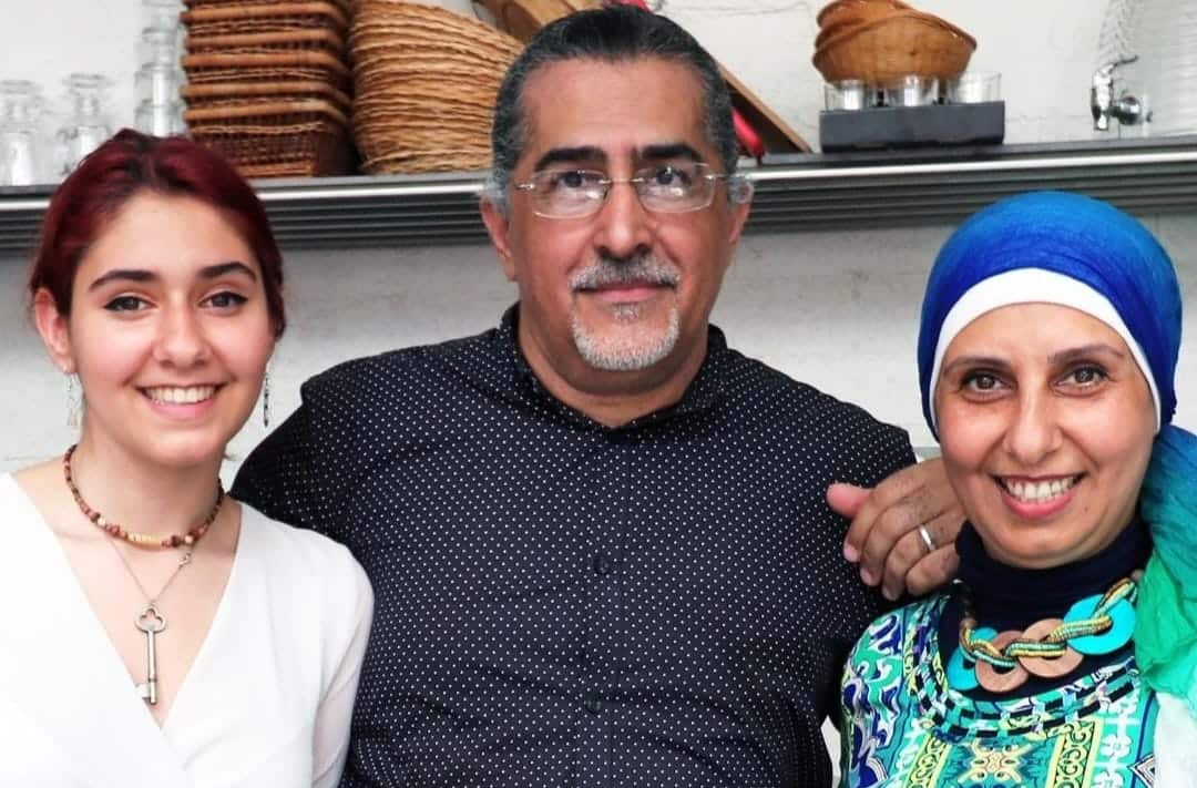 (left to right) A young woman, a man and a woman standing together inside 