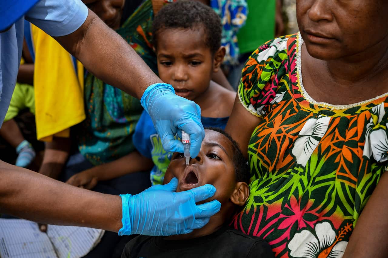 A nurse administers a child an oral vaccination