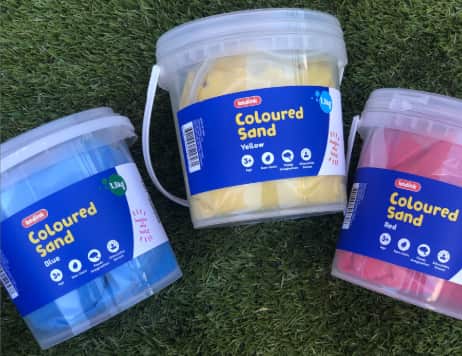 Buckets of blue, yellow, and red sand on a green backdrop.