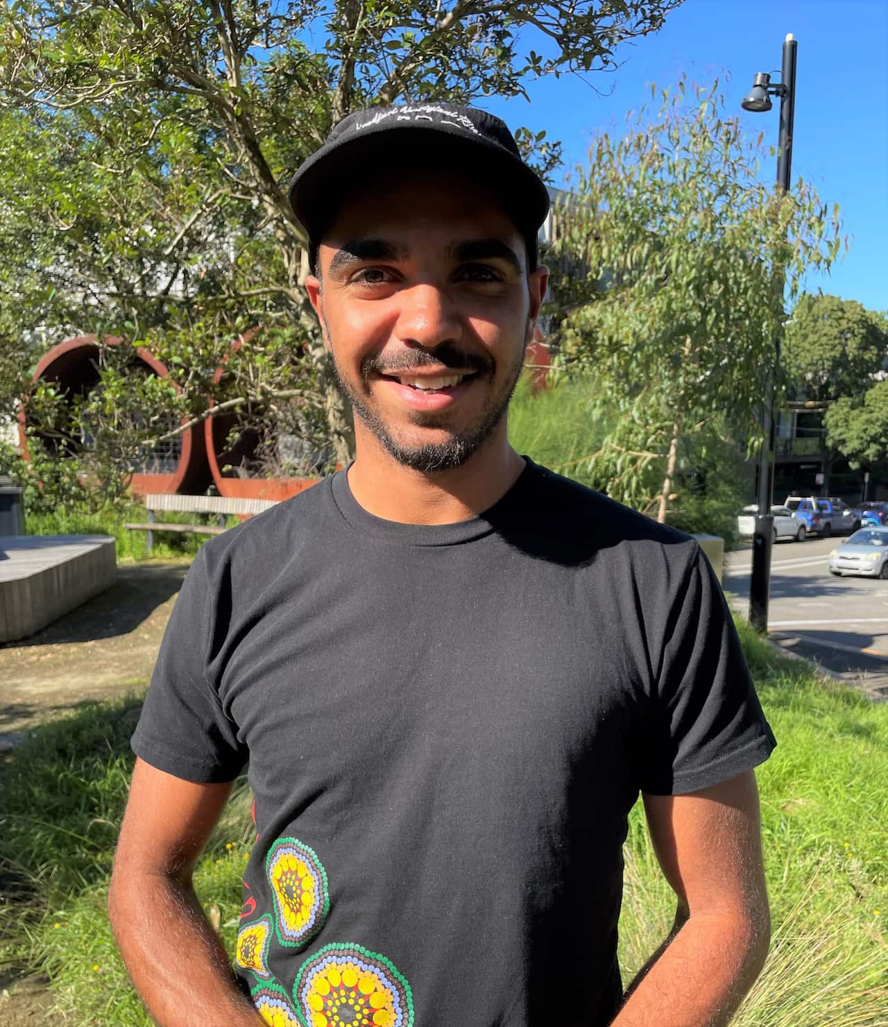 A man in a black T-shirt stands in a garden.