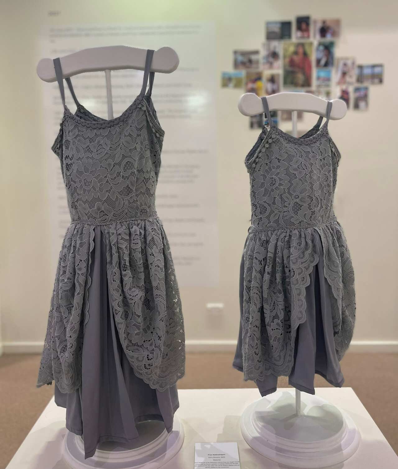 Two grey lace dresses holstered up on a coat hanger in an art gallery