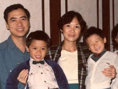 Two young Chinese boys are held by their mother, with their father on the left.