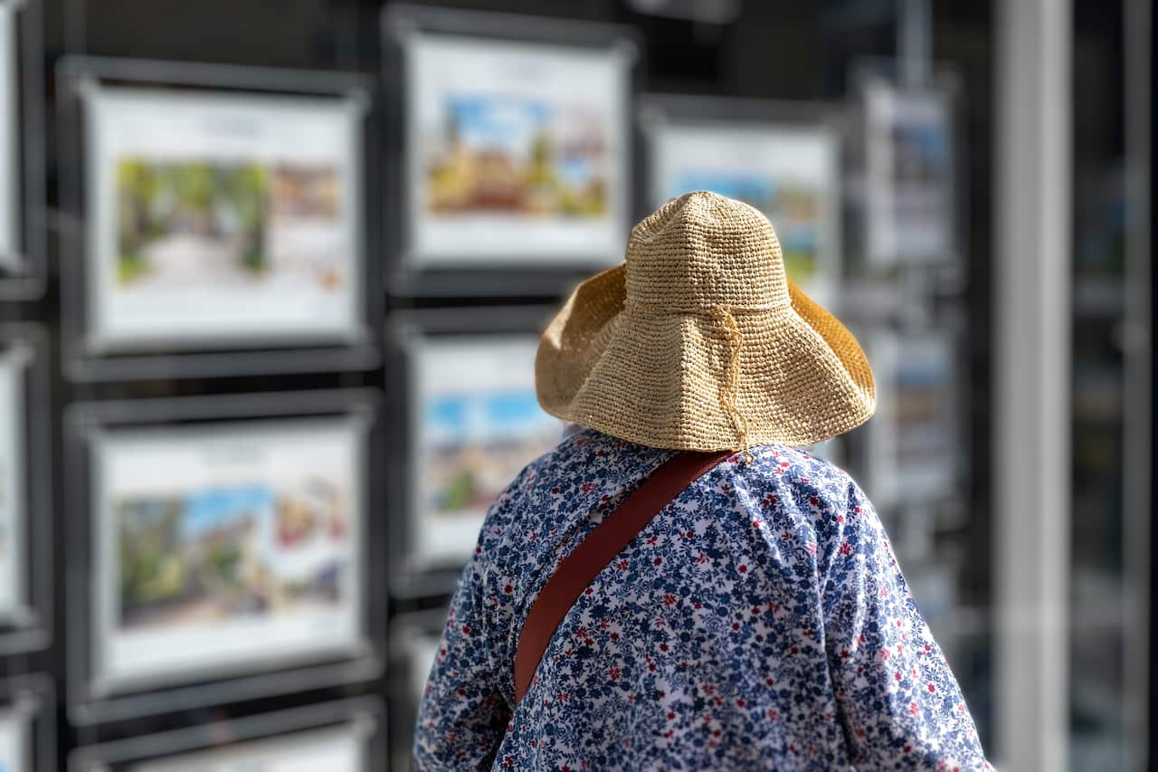 A woman looking at property advertisements in a window