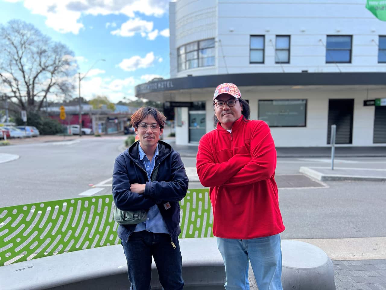 Two men standing by the road with their arms folded.