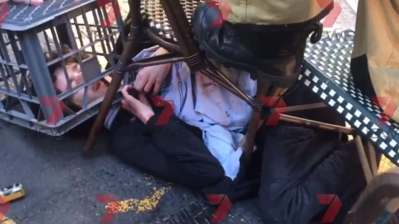 a man lying on the ground being held down with a crate over his head and two chairs