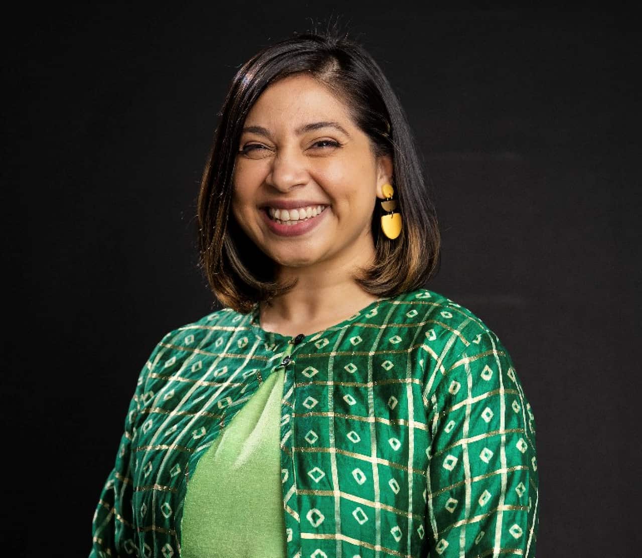Portrait of woman wearing green, smiling.