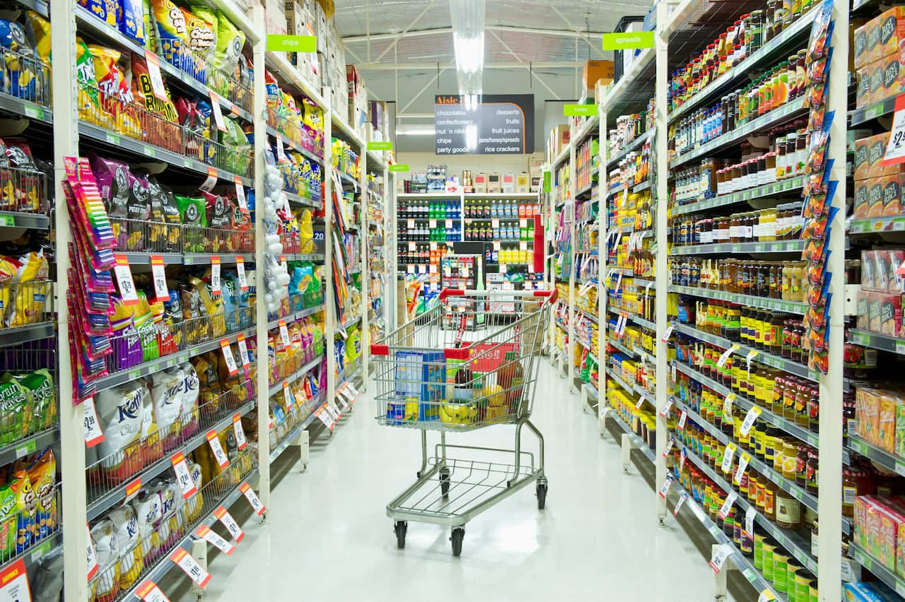 A trolley full of groceries in a supermarket aisle.