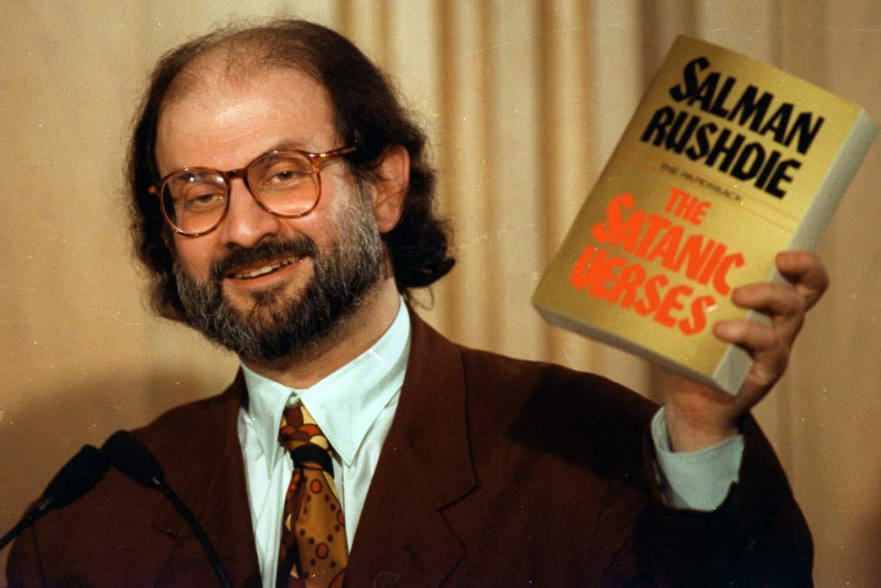 Salman Rushdie holds up a copy of his book.
