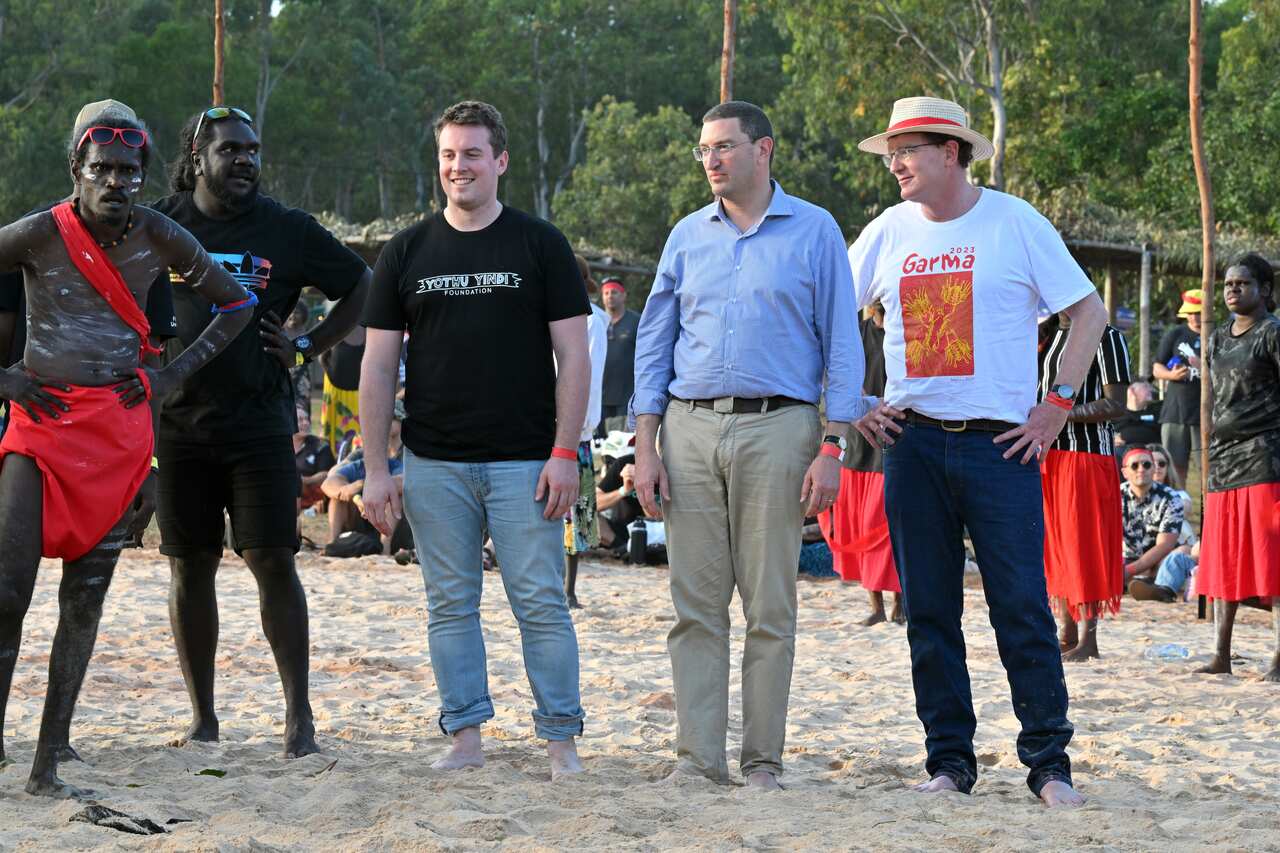 Four men standing on sand.