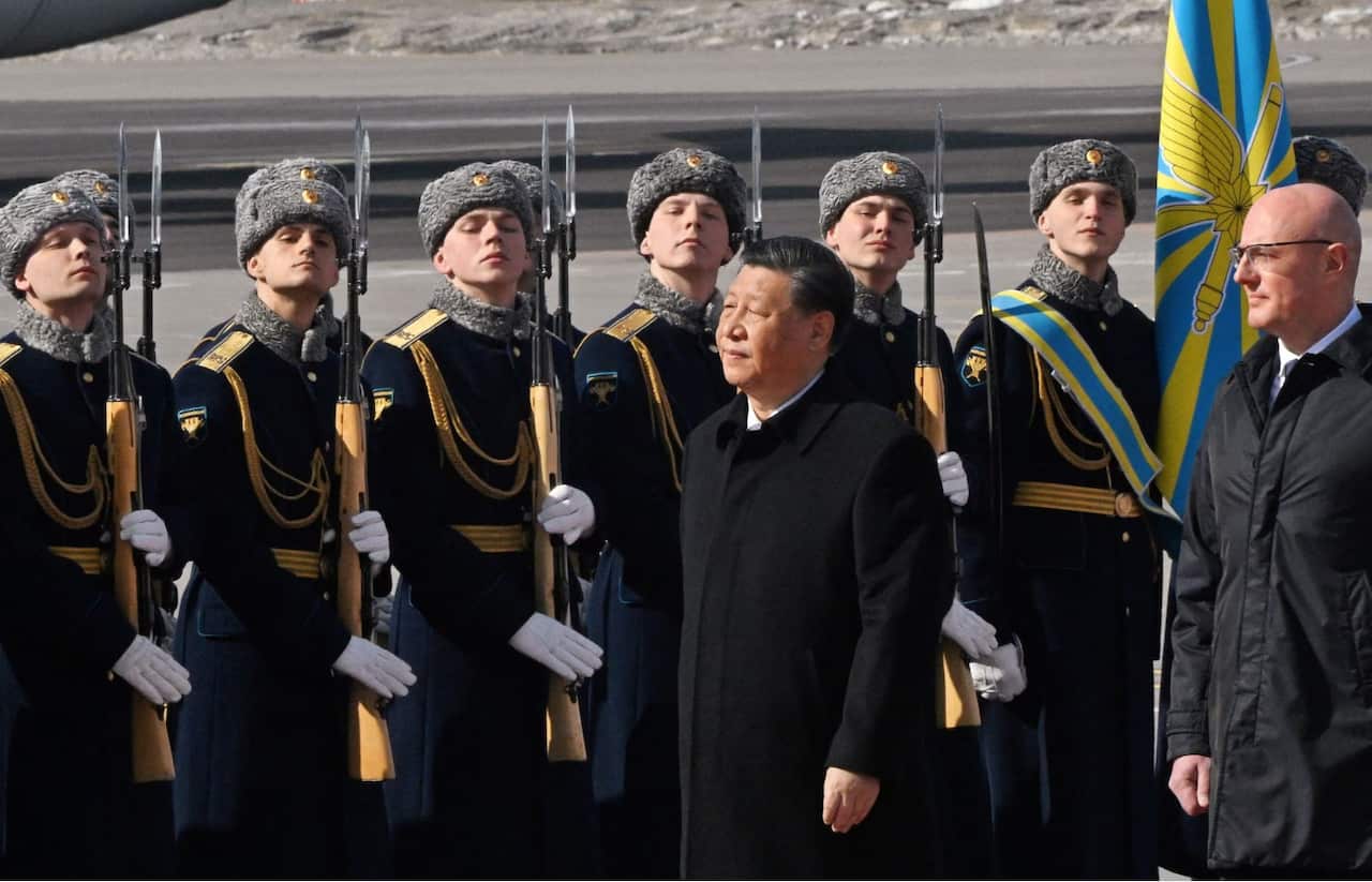 Chinese President Xi Jinping, accompanied by Russian Deputy Prime Minister Dmitry Chernyshenko, walks past honour guards and members of a military band during a welcoming ceremony upon his arrival at an airport in Moscow, Russia, March 20, 2023. Kommersant Photo/Anatoliy Zhdanov via REUTERS