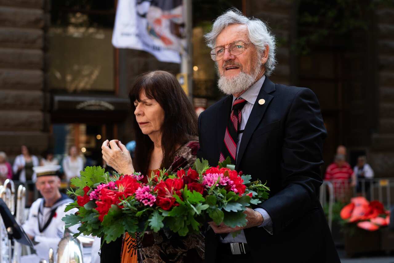 A woman closes her eyes alongside a man holding flowers.