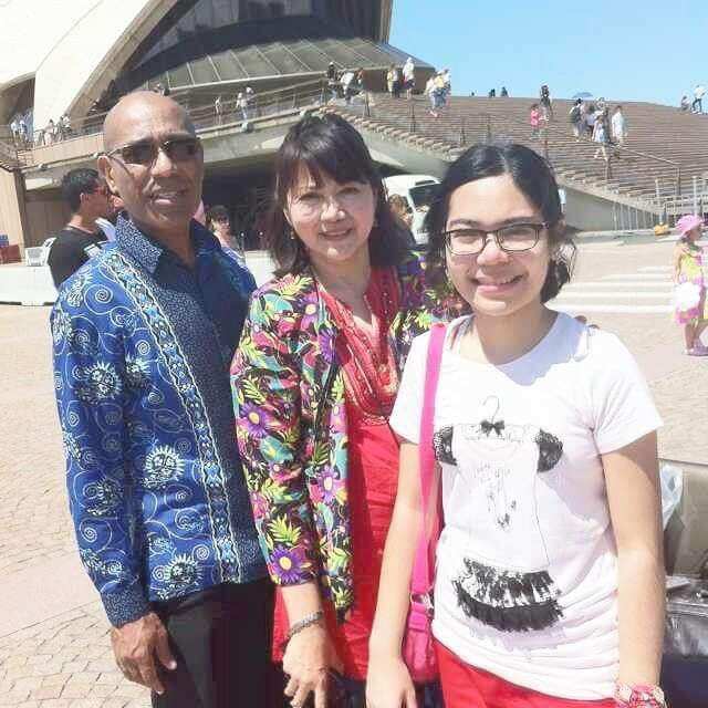 Julia with her mother and father standing in front of the Sydney Opera House.