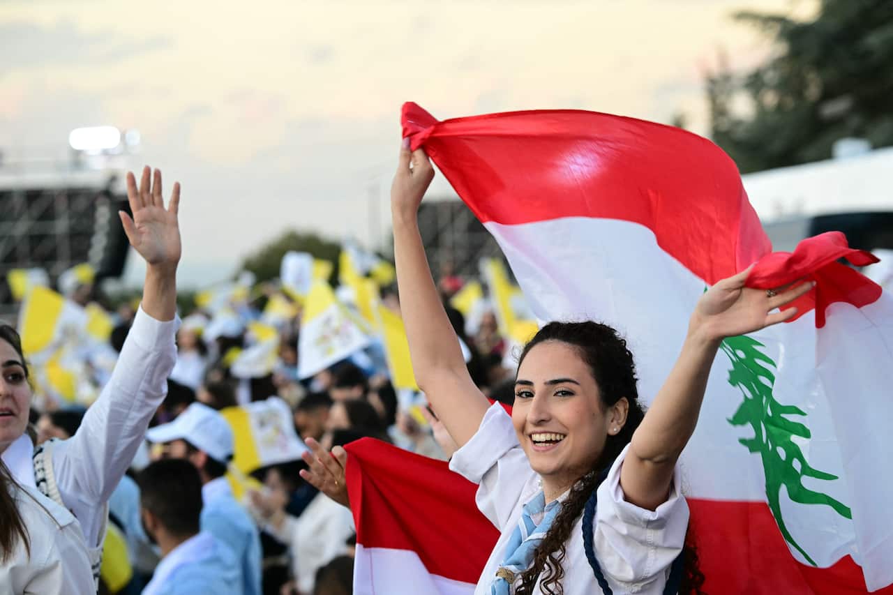 A woman waves a Lebanese flag among a crowd.