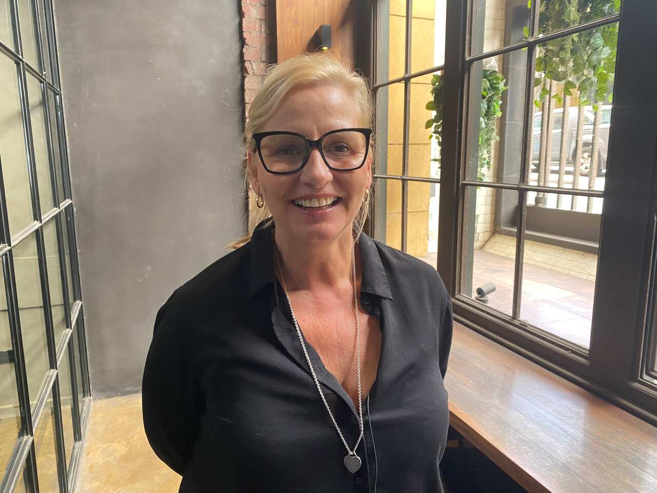 A blonde woman with a black shirt and glasses 