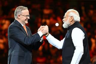 Anthony Albanese clasps Narendra Modi's hand in a show of strength during a community event.