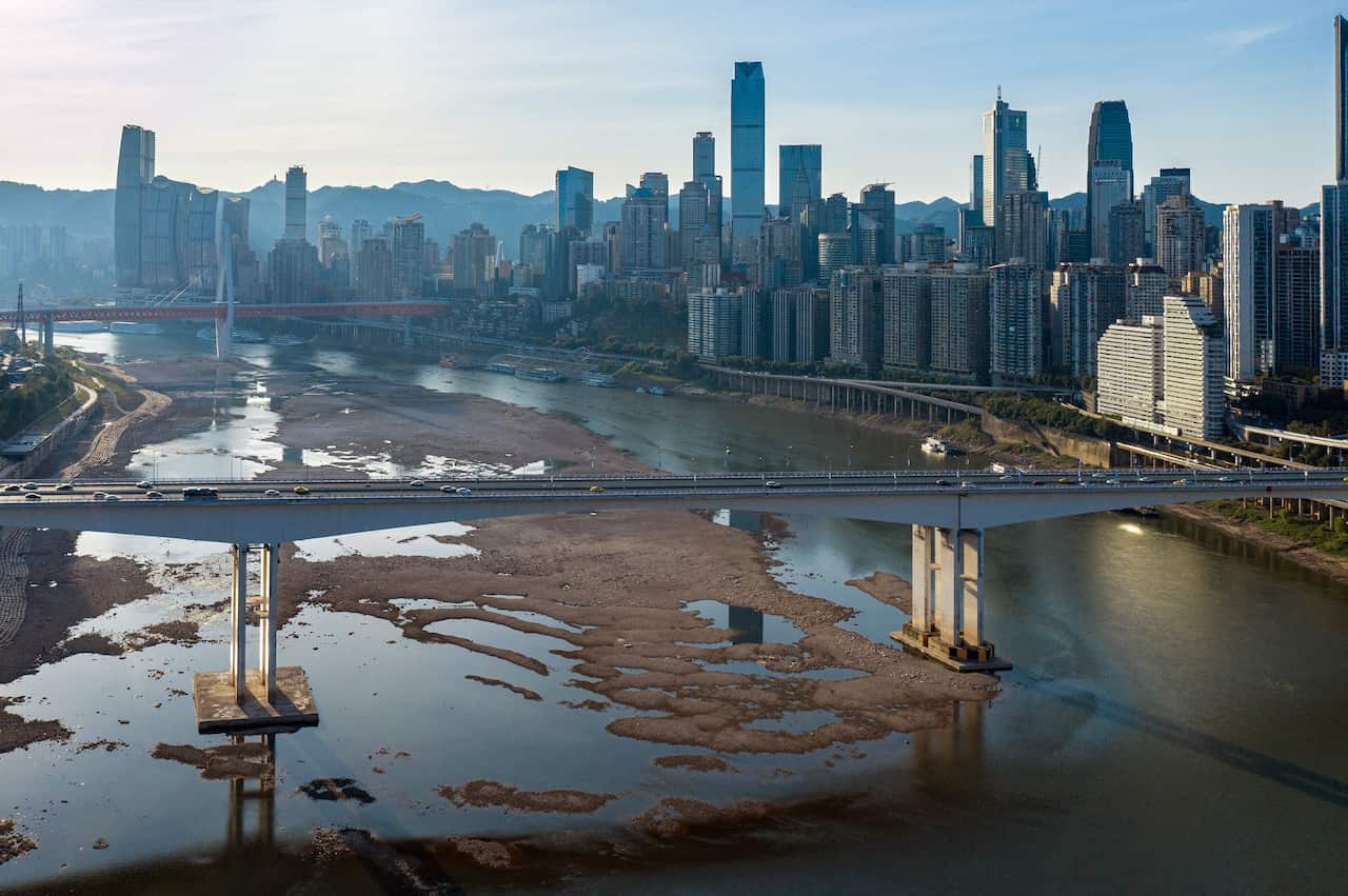 Aerial view of a partly-dried river, with city buildings in the background. 