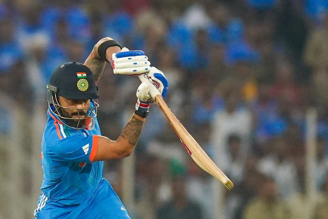 A man in a blue shirt holding a cricket bat