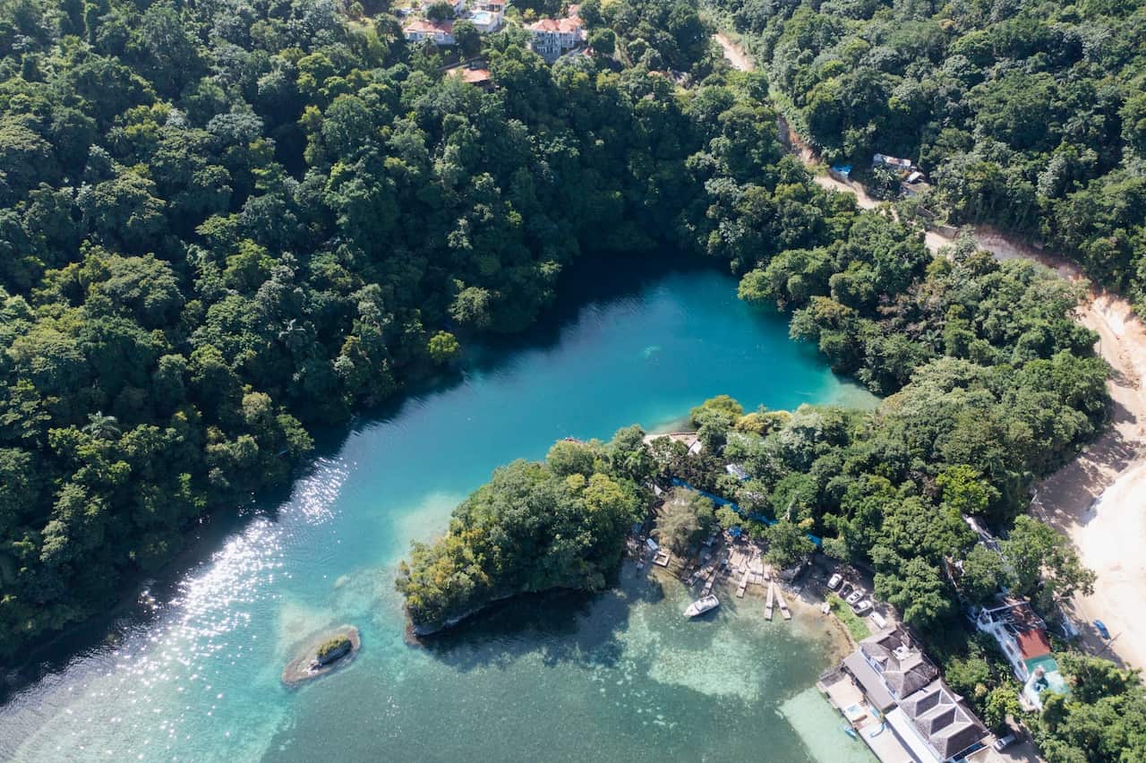 Aerial view of turquoise waters with thick bushland on one side 