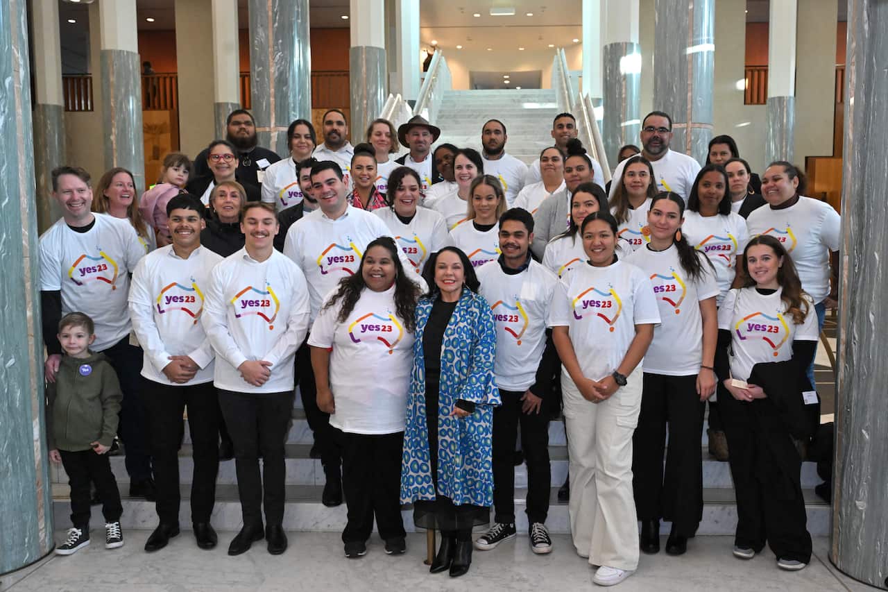 Woman poses with group of people in 'yes' t-shirts.