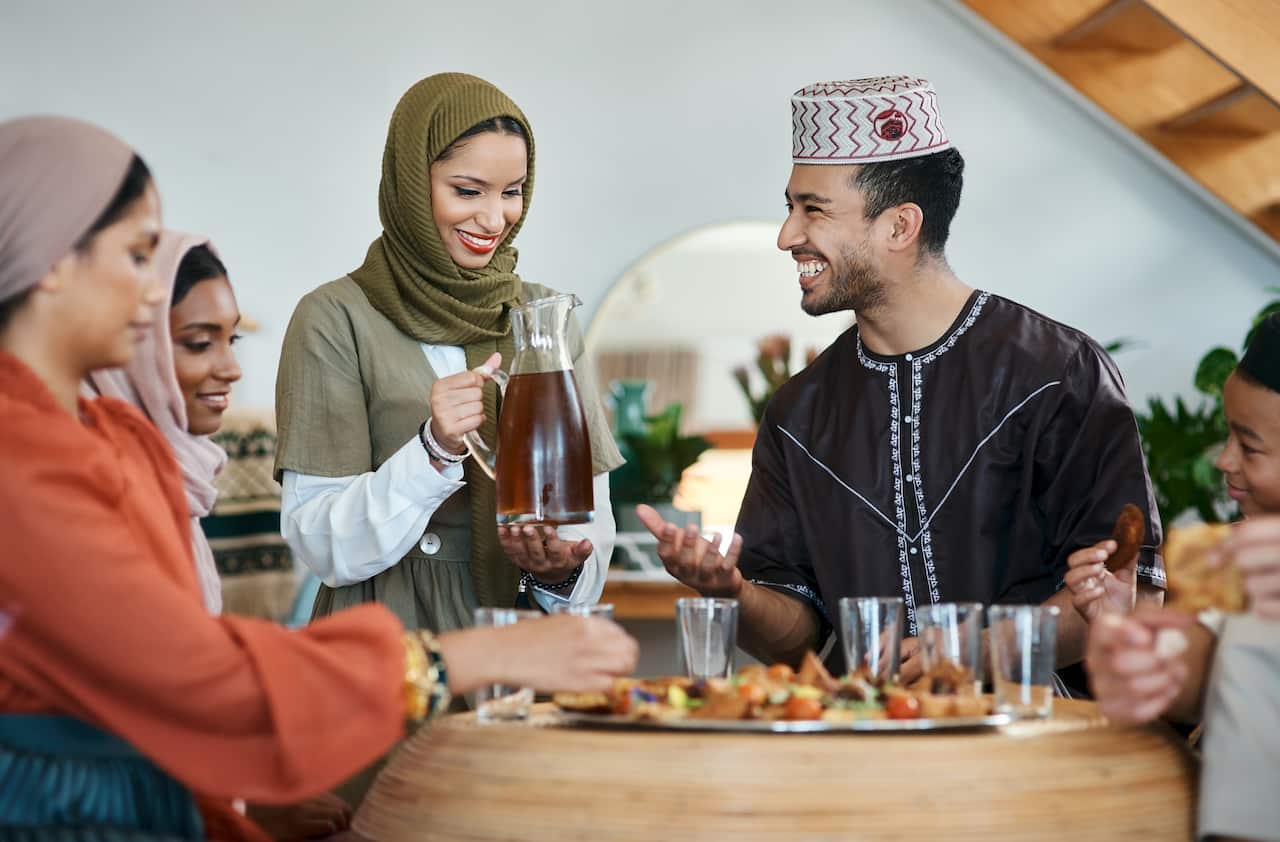Shot of a young muslim woman pouring drinks for her family
