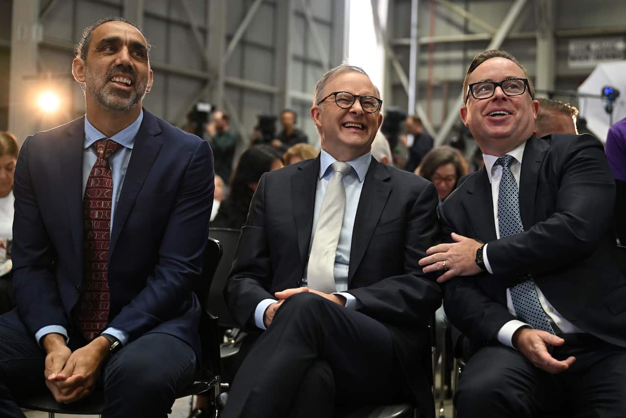 Three men in suits sitting and smiling.