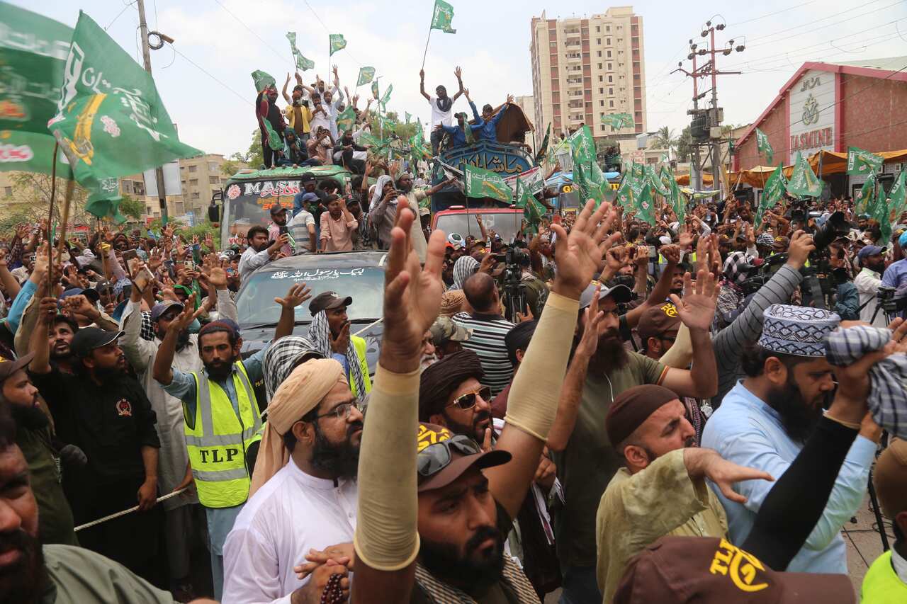 People participating in a protest, with flags and raising their hands.