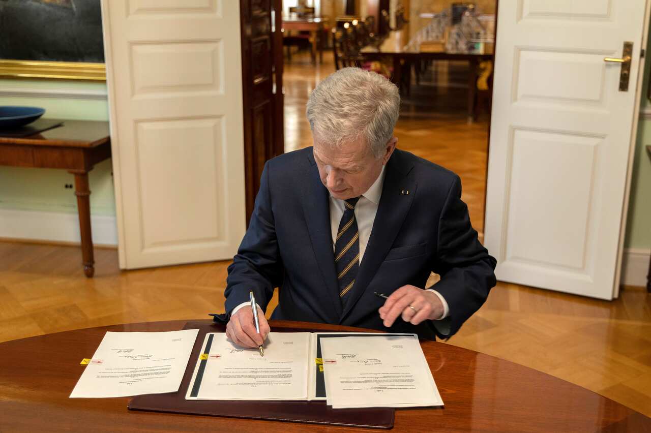 A man signing documents while seated at a table.