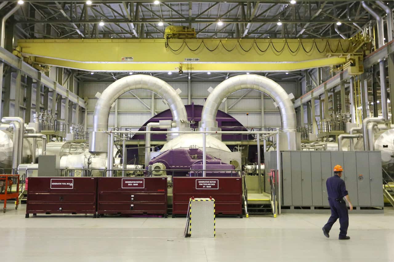 A man in a hard hat walks next to some steel equipment