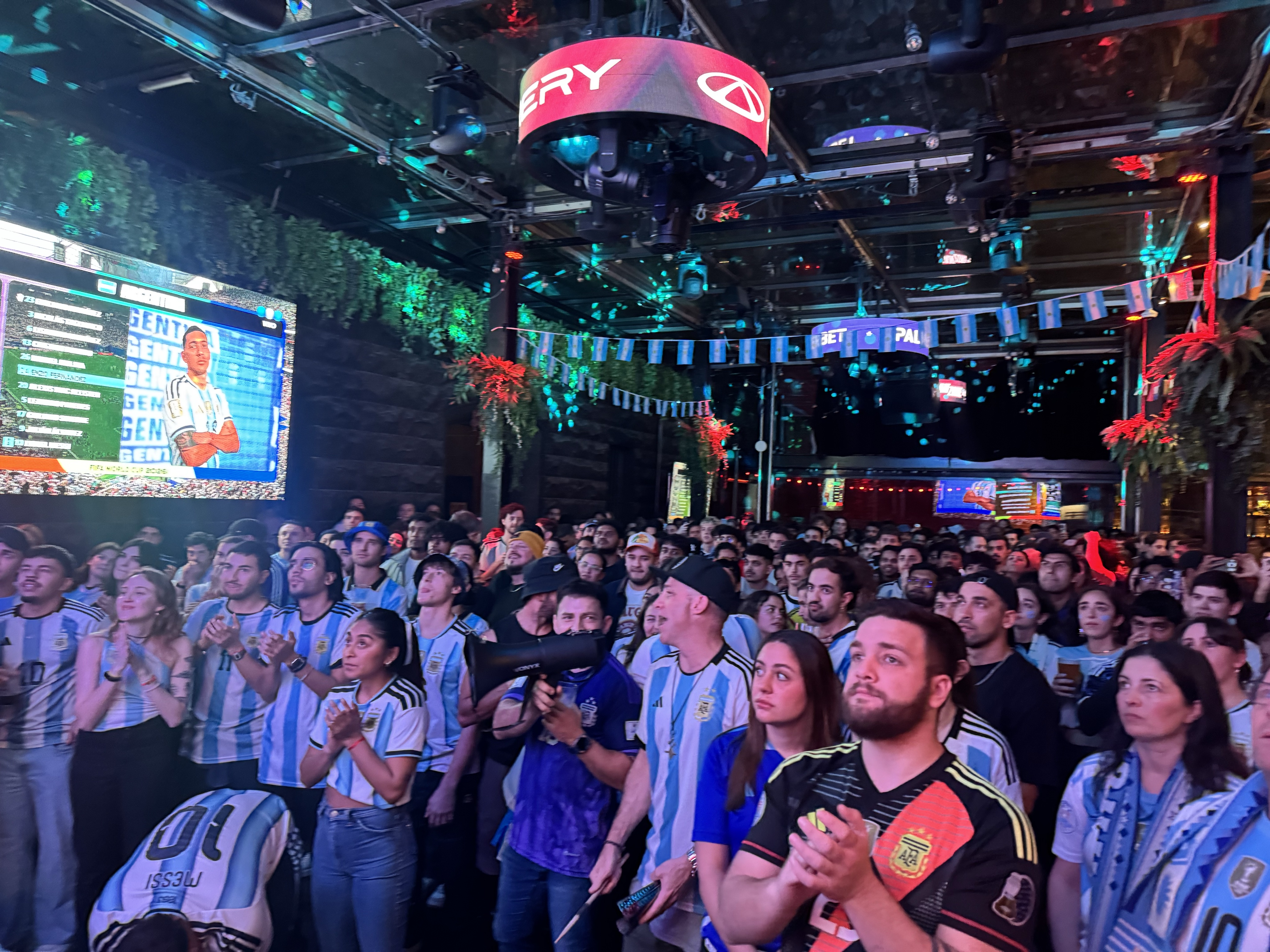 A large corwd for people in argentine jerseys look towards a screen