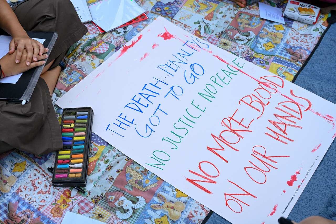 A hand-drawn sign that says "the death penalty's got to go. No justice, no peace. No more blood on our hands."