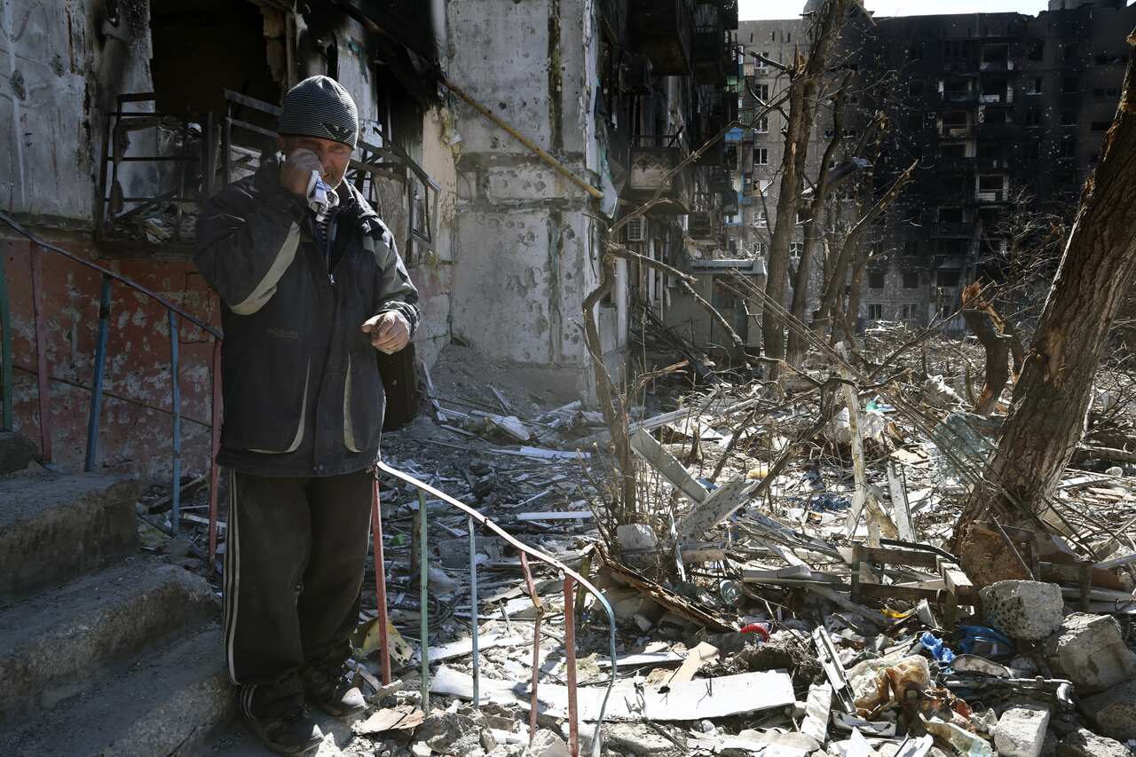 A man wipes his eyes in a street in Mariupol, Ukraine.
