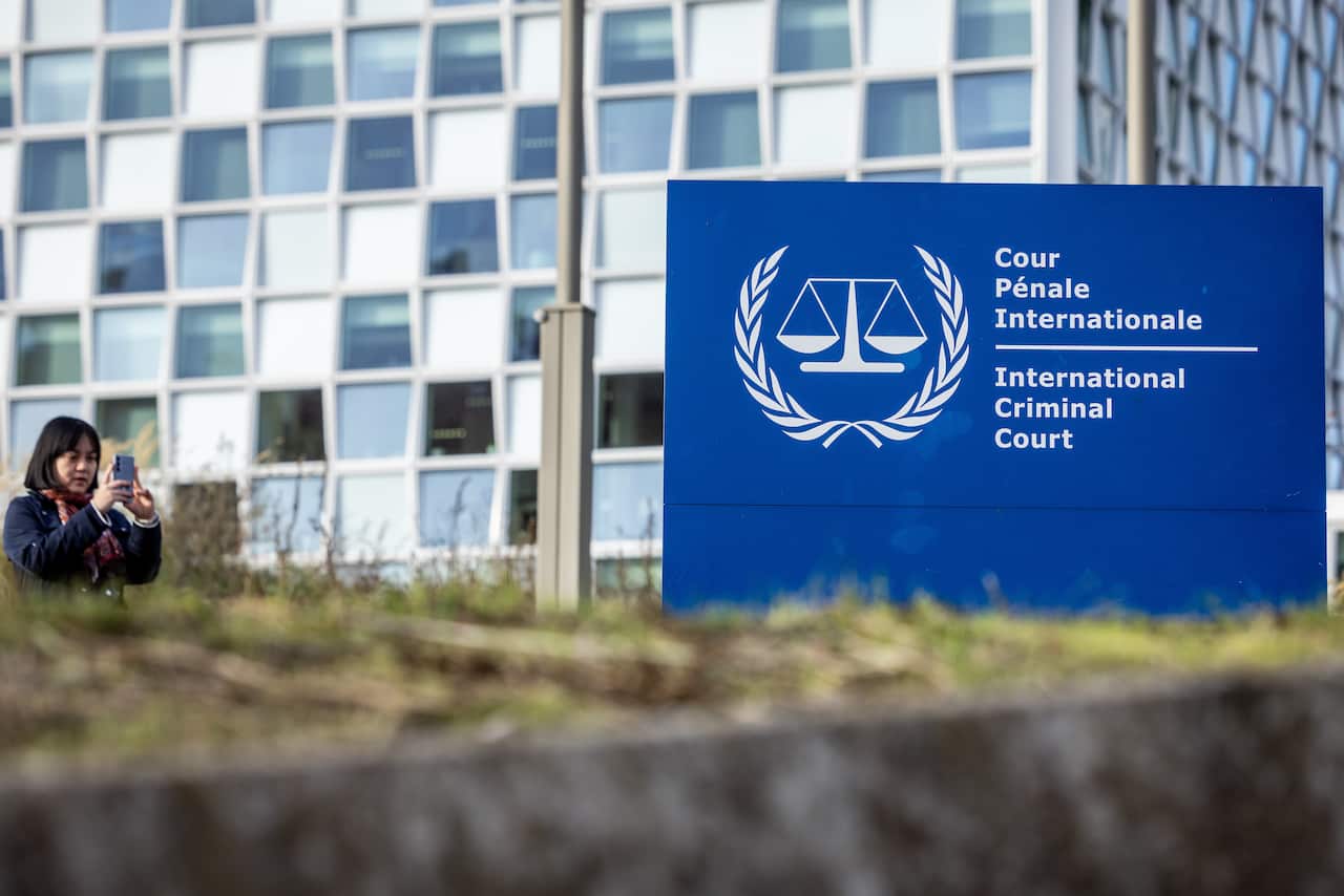 A signboard with the words International Criminal Court in the foreground, with the court's building in the background.