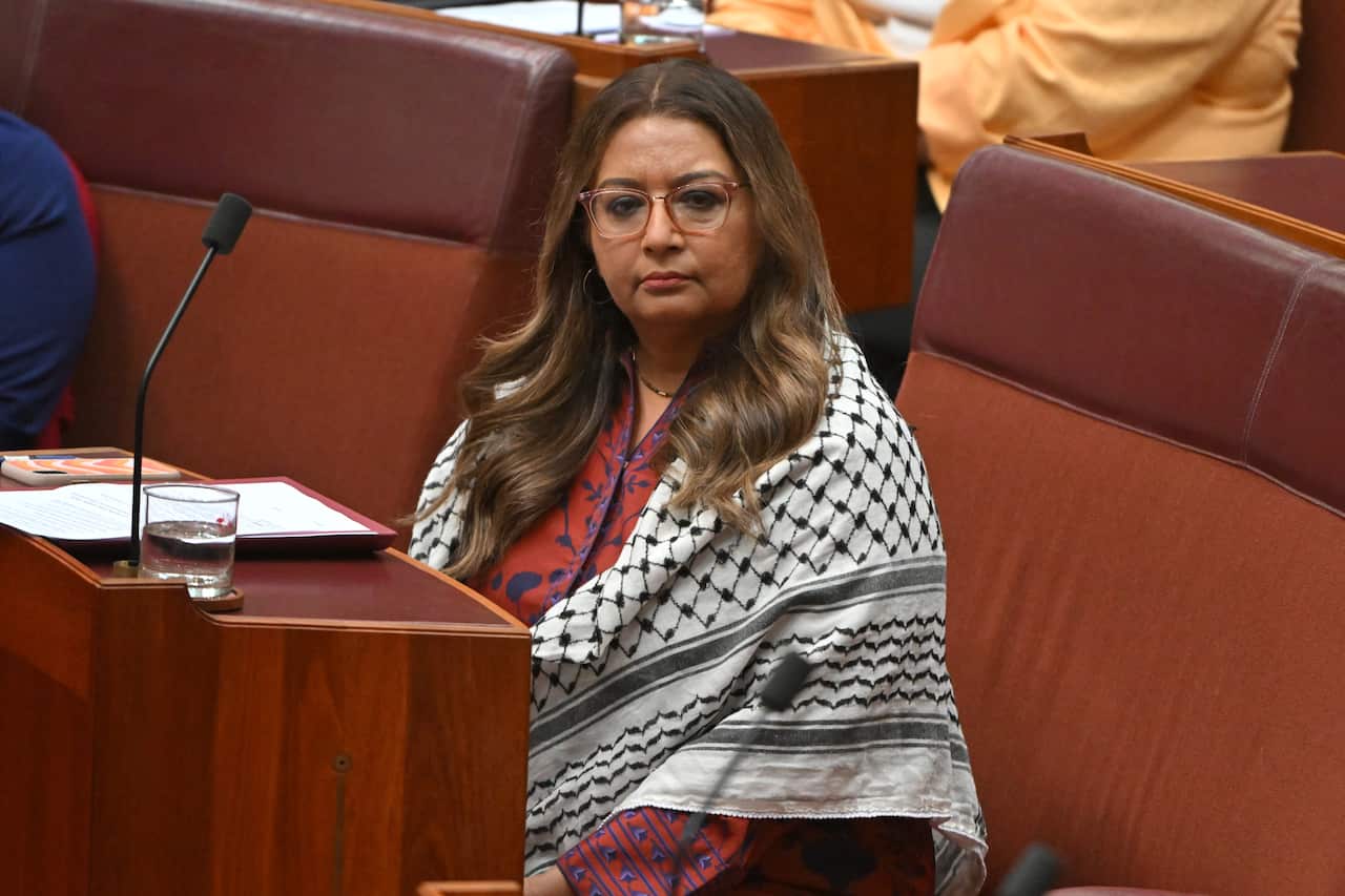 A woman sitting at a red desk wrapped in a black and white scarf