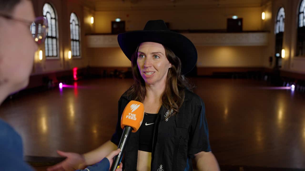 A woman in a cowboy hat with an orange microphone in front of her face