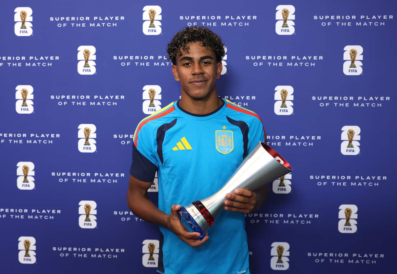 A Spanish football player holding up a silver trophy.