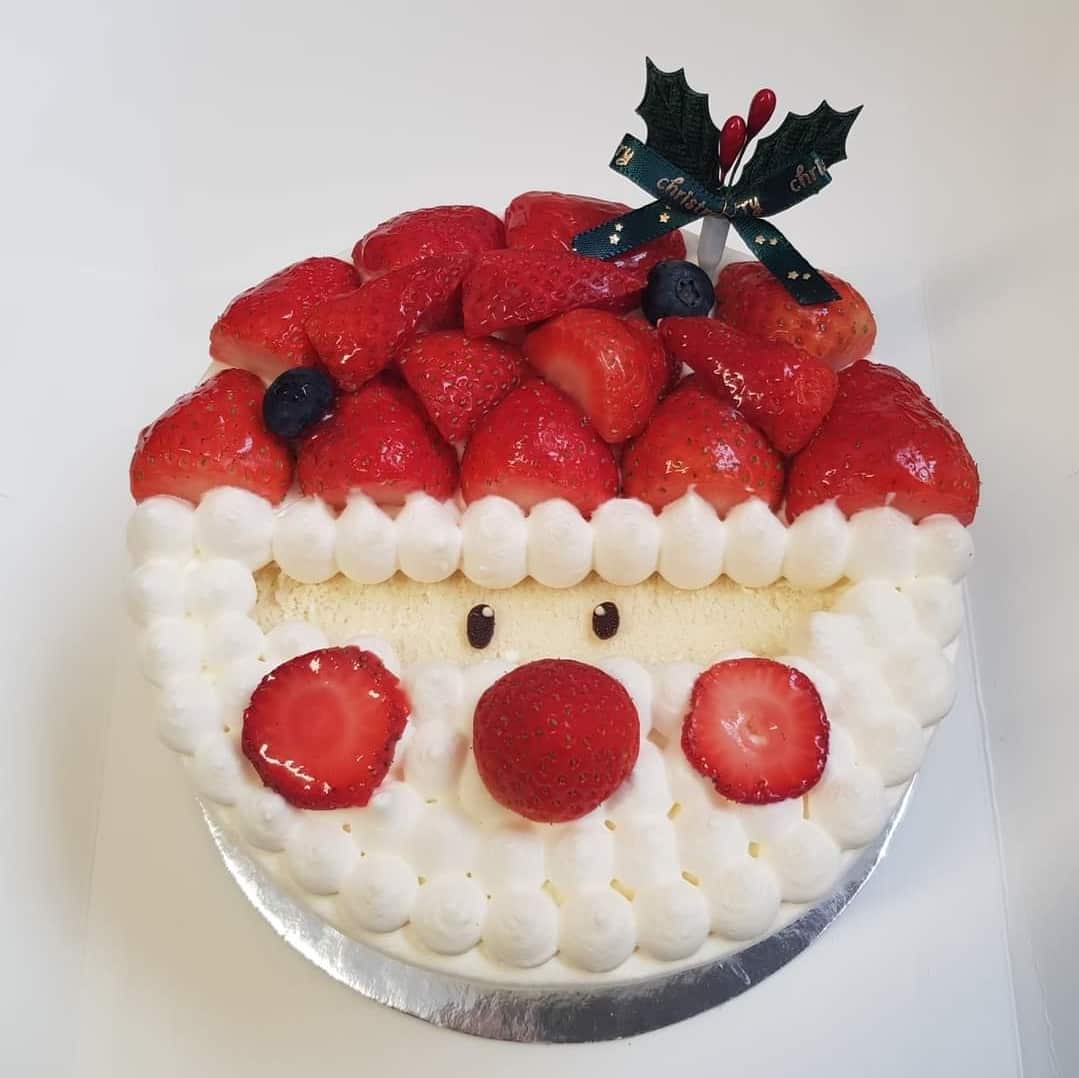 Cake decorated with strawberries and cream in shape of Santa Clause face